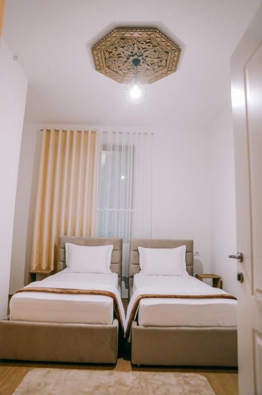 two beds in a small room with a window at Vila Franko in Berat