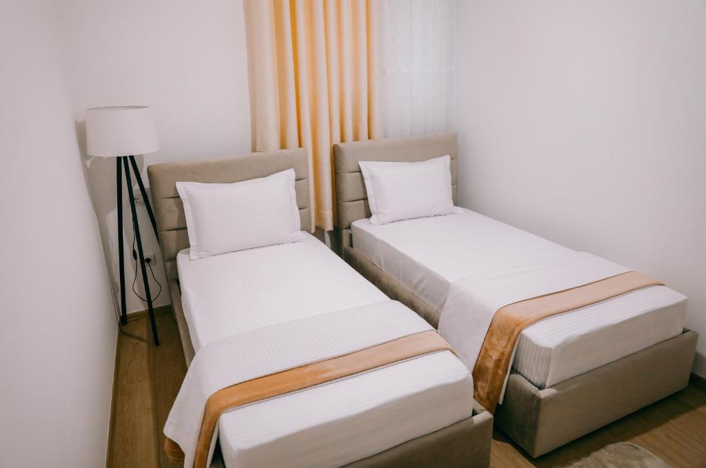 two beds in a small room with a lamp at Vila Franko in Berat