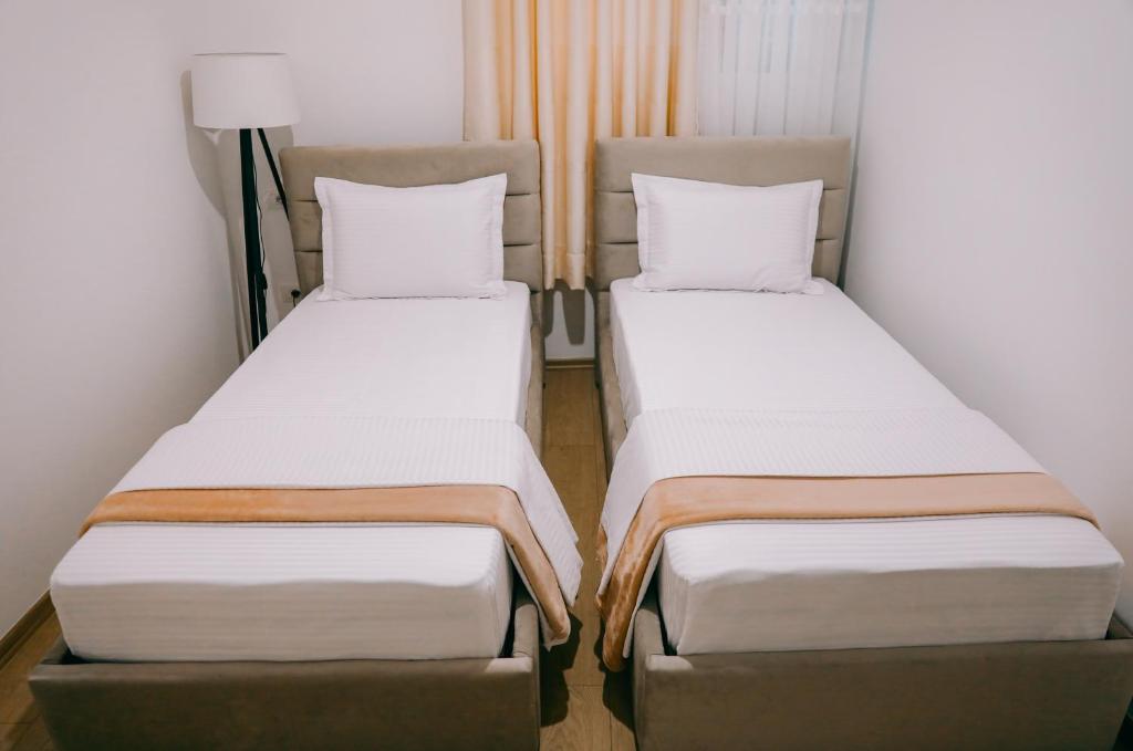 two twin beds in a small room with a lamp at Vila Franko in Berat