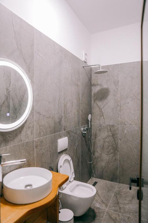 a bathroom with a sink and a toilet and a mirror at Vila Franko in Berat