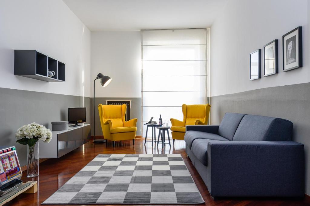 sala de estar con sofá azul y sillas amarillas en ALTIDO Lovely Apt with Terrace and View in Central Milan, en Milán