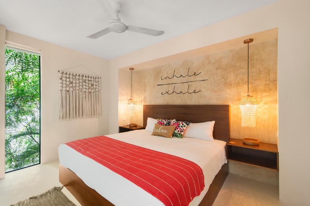 een slaapkamer met een bed met een rode en witte deken bij KAHATSA' boutique hotel in Tulum