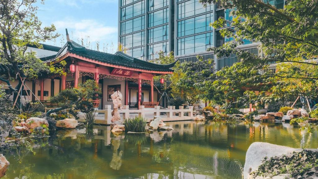 a temple in a pond in front of a building at 苏州山塘街华贸姑苏里酒店公寓 in Suzhou