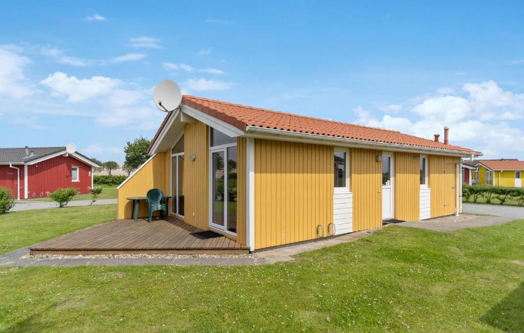 a small yellow building with a wooden deck at Friedrichskoog-Deichblick 20 in Friedrichskoog
