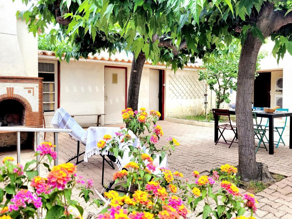 - une table, des chaises et des fleurs dans la cour dans l'établissement Maison T4 climatisée, parking, véranda, jardin clos, proche plage et commerces, idéale 6 personnes - FR-1-794-137, à Canet