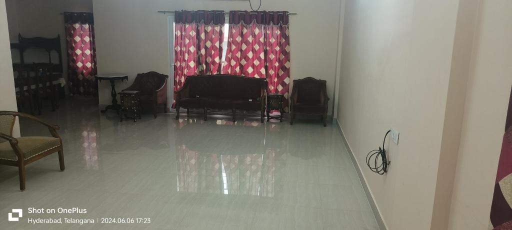 a room with chairs and a table and curtains at Sakez Homestays K in Hyderabad