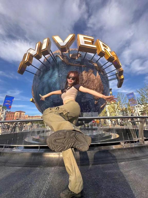 a woman is posing in front of a sign at Happy Dragon Universal Vacation Hotel - close to Universal Studio and Wanda Plaza,free shuttle to the Resort,Free Coffee,Laundry in Beijing