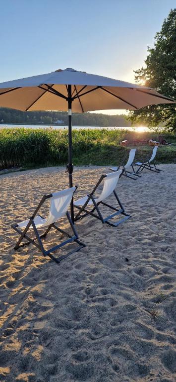 three chairs and an umbrella on a beach at Szary Domek Mikołajki in Mikołajki