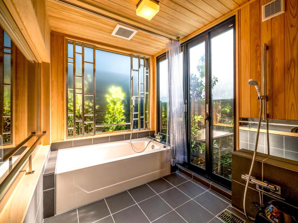 a bathroom with a tub and a large window at HOTEL R9 Kujukuri "ex Casual Resort COFF Ichinomiya" in Ichinomiya