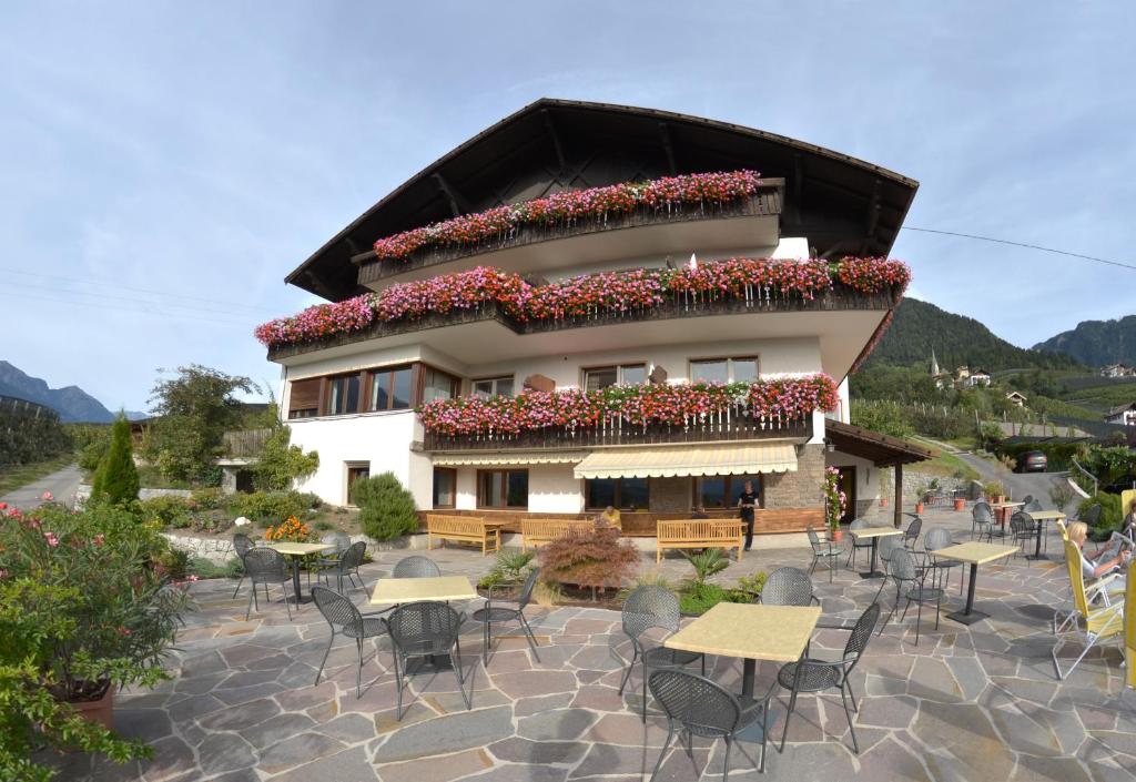 a building with tables and chairs in front of it at Pension Obertaberhof in Schenna