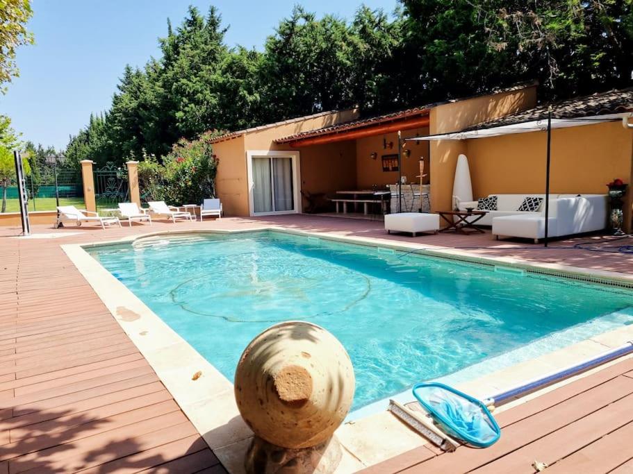 une grande piscine avec une terrasse en bois et une maison dans l'établissement Avignon grande villa avec piscine sans vis à vis, à Avignon