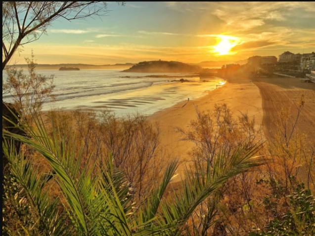 a view of a beach with the sun setting at Hospedaje Botin in Santander