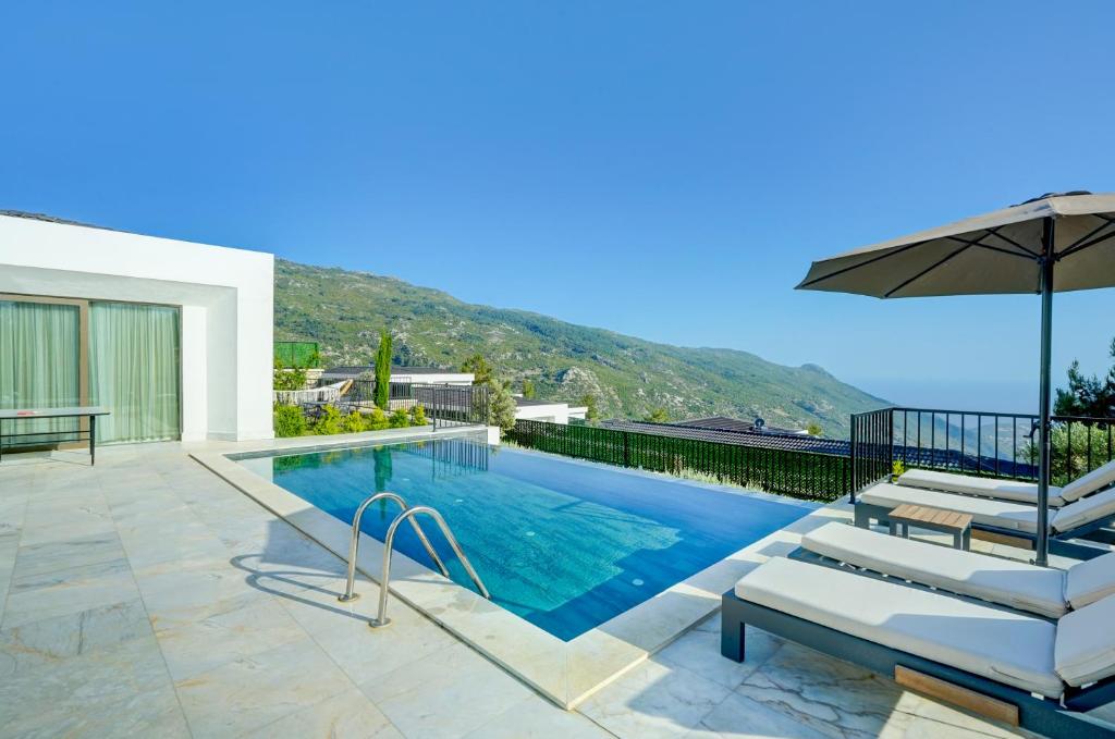 a swimming pool with two chairs and an umbrella at Villa Pluto 1 - PLANET LUXURY VILLAS in İslâmlar