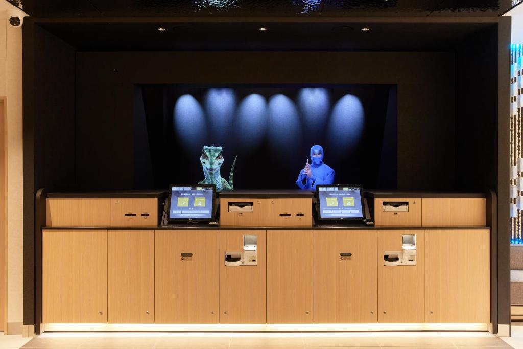 Una pantalla de televisión con dos computadoras portátiles al frente en Henn na Hotel Premier Kagoshima Tenmonkan, en Kagoshima