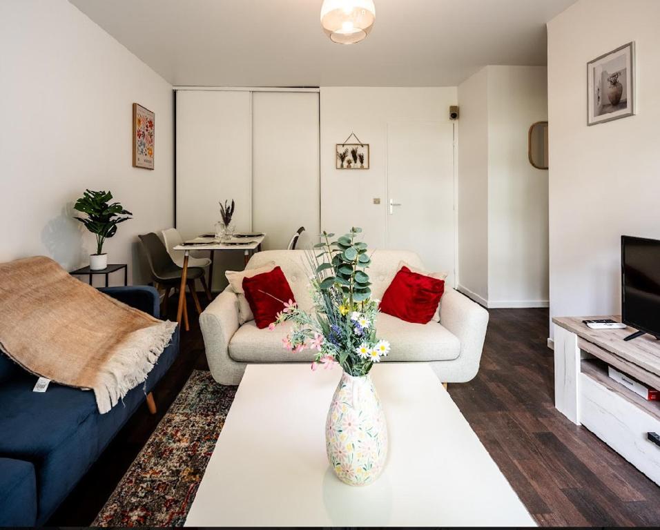 un salon avec un vase et des fleurs sur une table dans l'établissement Le Havre de paix à Suresnes, à Suresnes