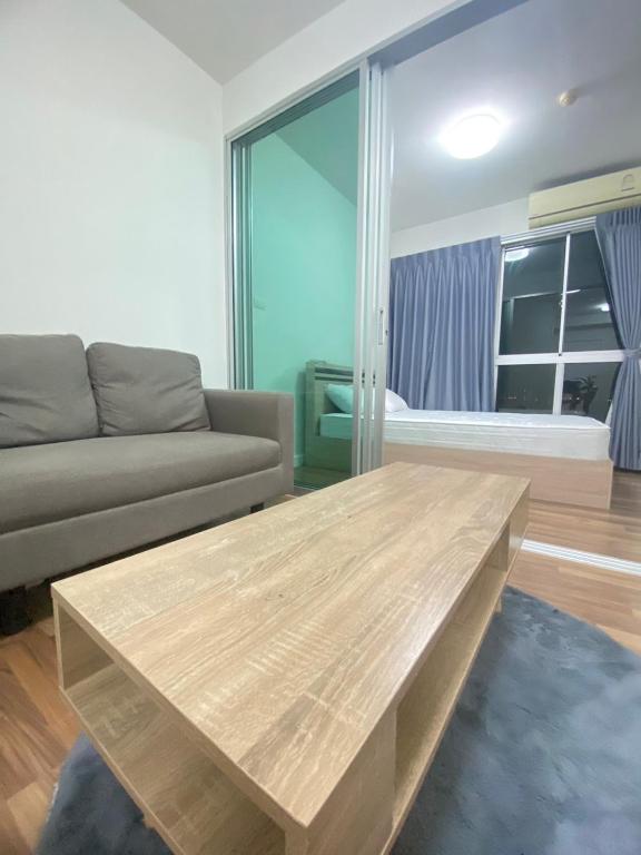 a living room with a couch and a wooden table at Mari Space in Nonthaburi