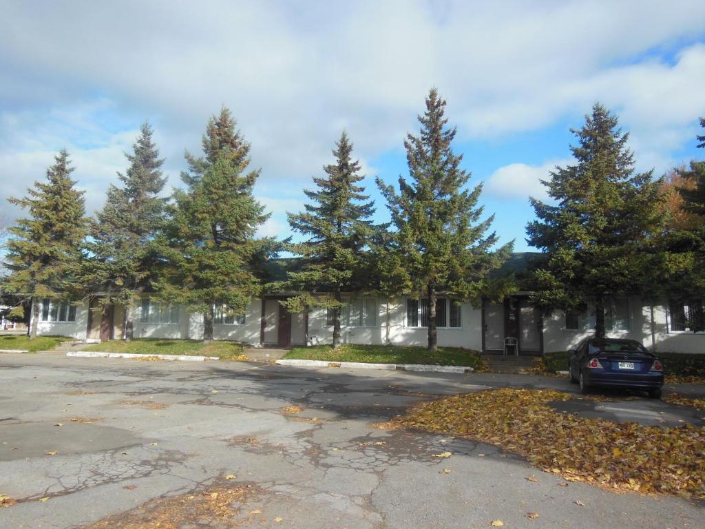 ein Auto, das vor einem Haus mit Bäumen parkt in der Unterkunft Motel Le Paysan in Montreal