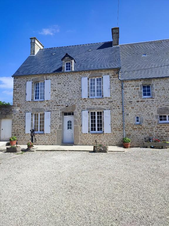 une grande maison en briques avec des volets blancs dans l'établissement La Barberie à Saint-Marcouf, à Saint-Marcouf