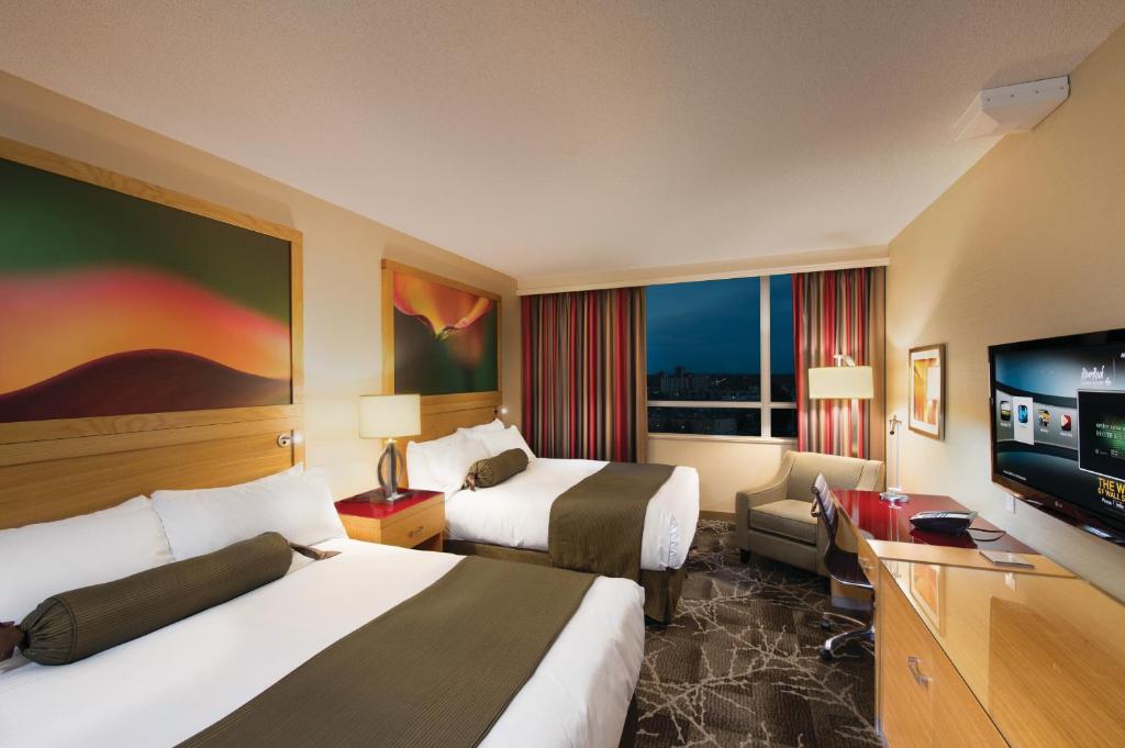 a hotel room with two beds and a flat screen tv at River Rock Casino Hotel in Richmond