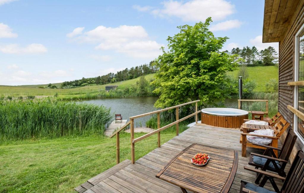 a wooden deck with a table and chairs on a lake at Lovely Home In Ugerløse With Kitchen in Ugerløse