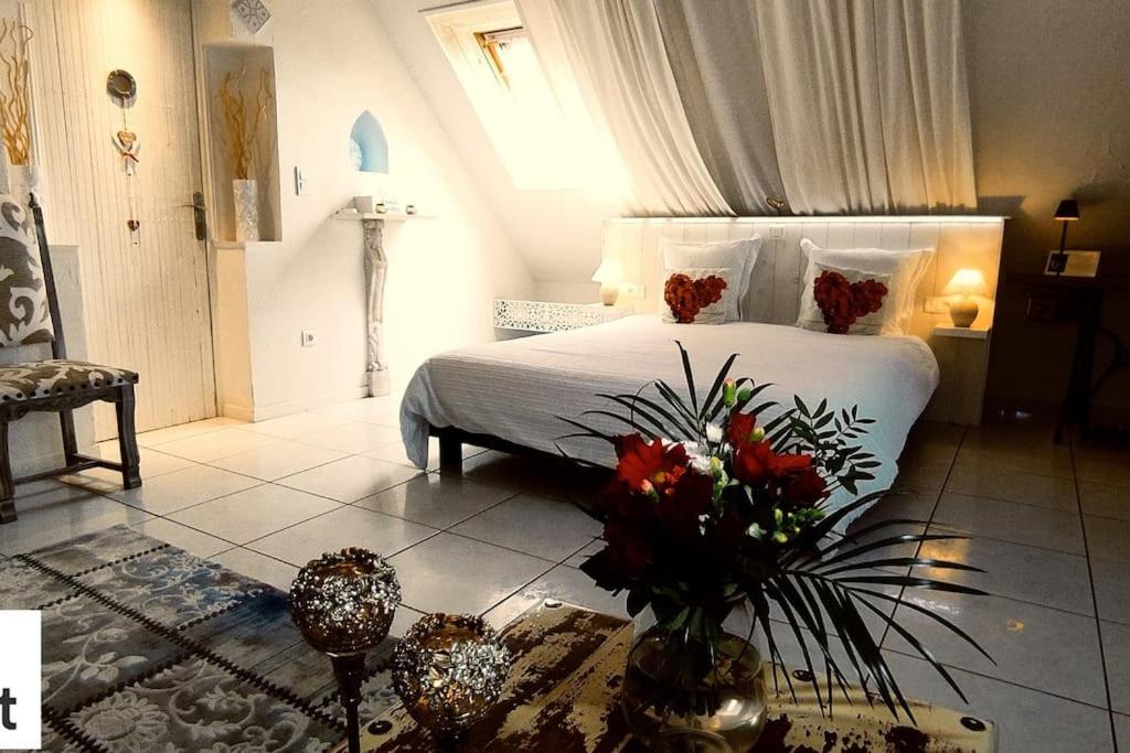 une chambre avec un lit avec des fleurs sur une table dans l'établissement Logement de charme proche Colmar avec terrasse, à Sainte-Croix-en-Plaine