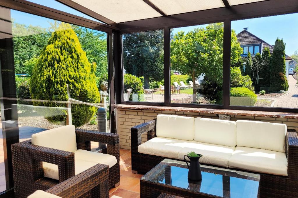 a screened in porch with chairs and a glass table at Moderne 1 Zimmer Ferienwohnung im Landhaus Haffkrug mit Terrasse, Gartenblick und Parkplatz in ruhiger Lage in Scharbeutz