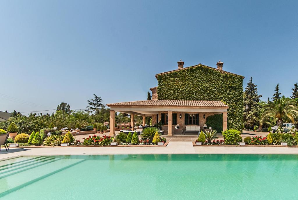 a house with a swimming pool in front of a building at Villa Santa María Dreams AWARDED 2024 in Santa Maria del Camí