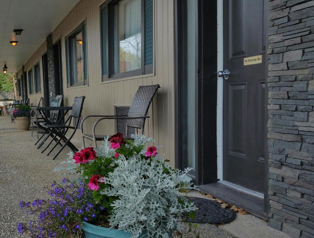 eine Veranda mit zwei Stühlen und Blumen vor einer Tür in der Unterkunft Maple Leaf Motel Emerson in Emerson