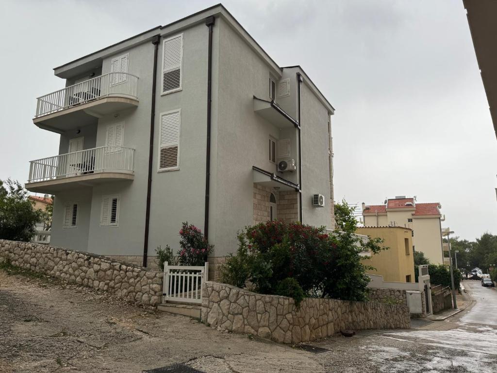 a large white building with balconies and a stone wall at House 100m from the beach with free parking in Baška Voda