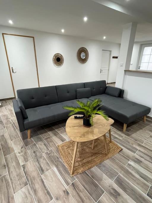 un salon avec un canapé noir et une table dans l'établissement La maison des hôtes, à Poilly-lez-Gien