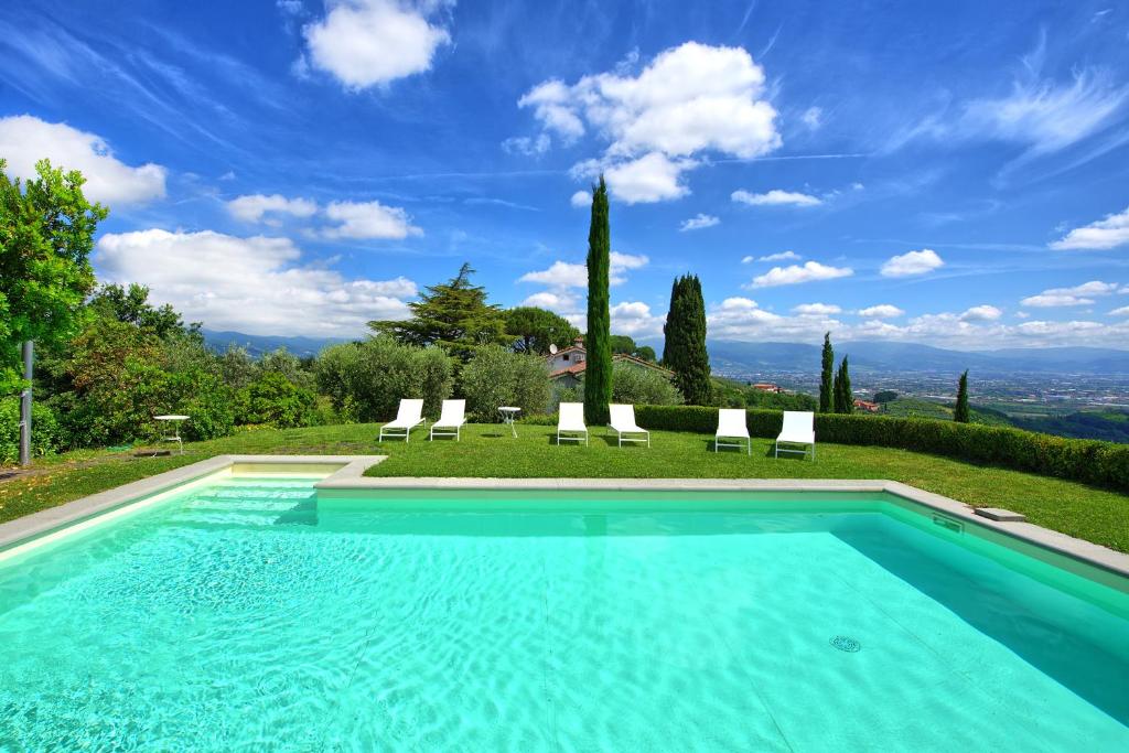 a pool with chairs and a view of the mountains at Villa Mami by PosarelliVillas in Serravalle Pistoiese