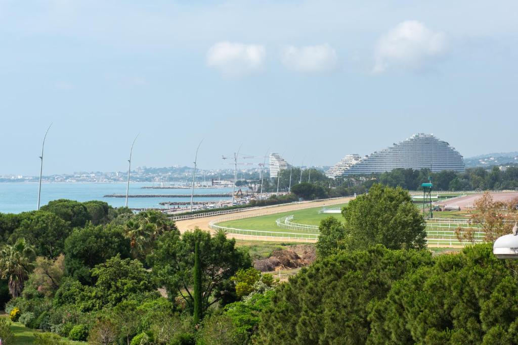 - une vue sur un parc arboré et l'eau dans l'établissement Appartement vue mer, à Cagnes-sur-Mer