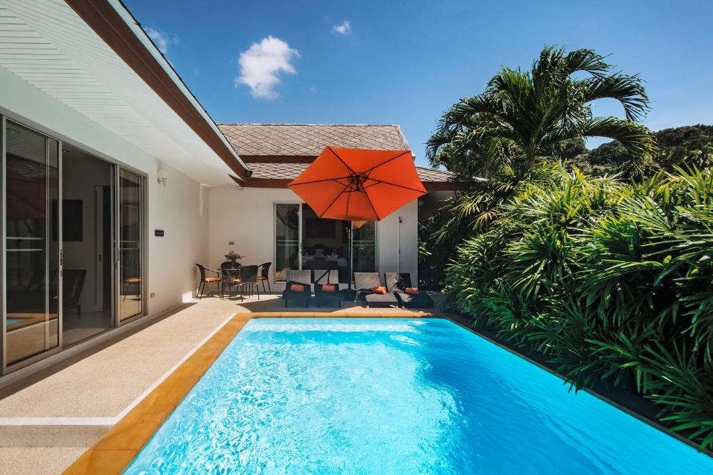 una piscina con sombrilla y una casa en Villa Thailee, en Ao Nang Beach
