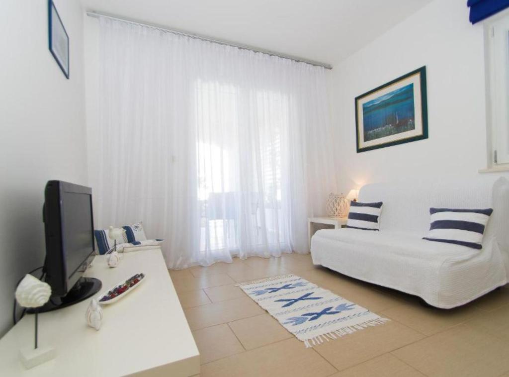 - un salon avec un canapé blanc et une télévision dans l'établissement Apartments Villa Olea, à Lumbarda