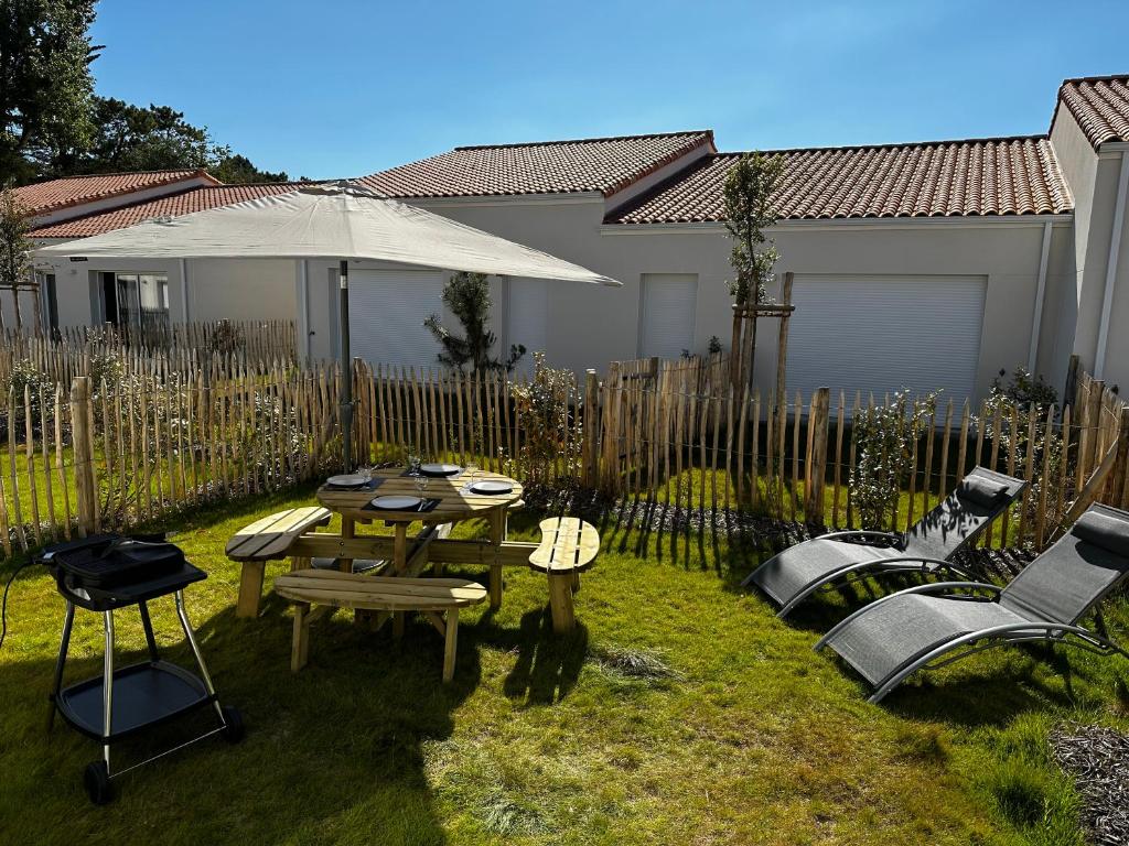 a backyard with a table and chairs and an umbrella at Charmante maison entre mer et forêt in Saint-Jean-de-Monts