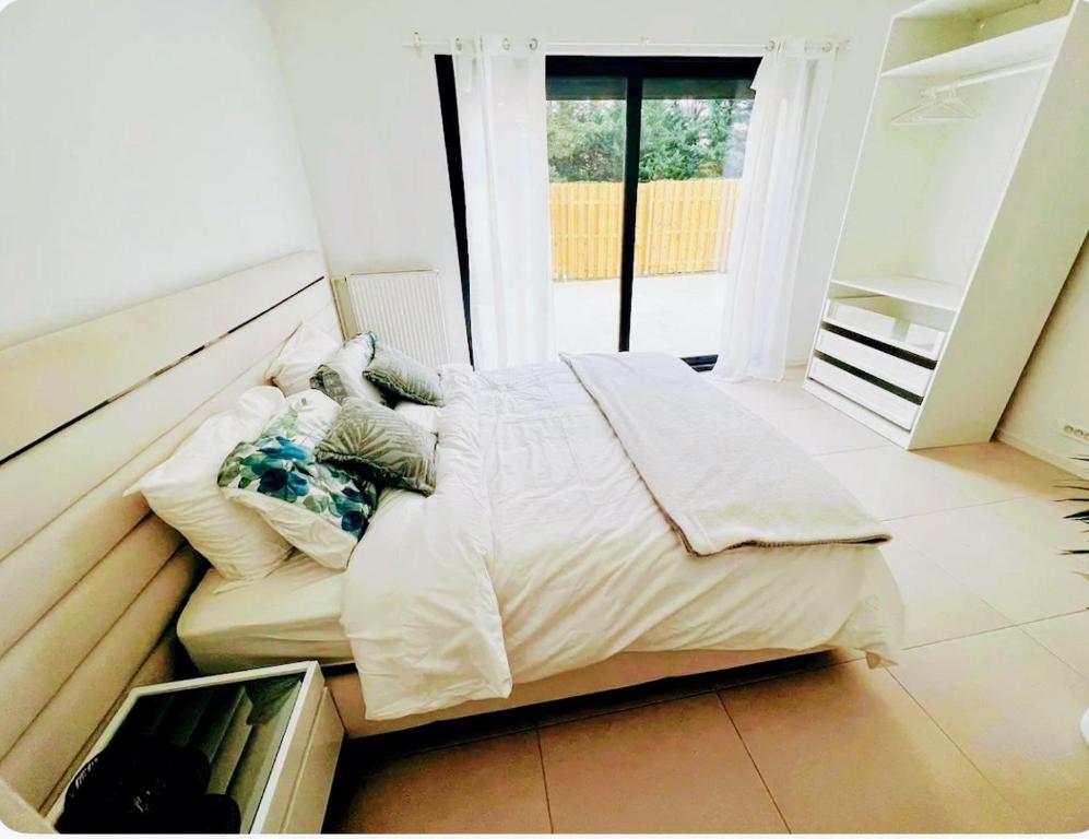 un grand lit dans une chambre avec une fenêtre dans l'établissement Très belle maison lac d Enghien les bains 15 min Paris, à Saint-Gratien