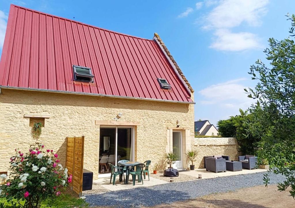 une maison en briques avec un toit rouge et une table dans l'établissement Normandie entre campagne et mer, à Émiéville