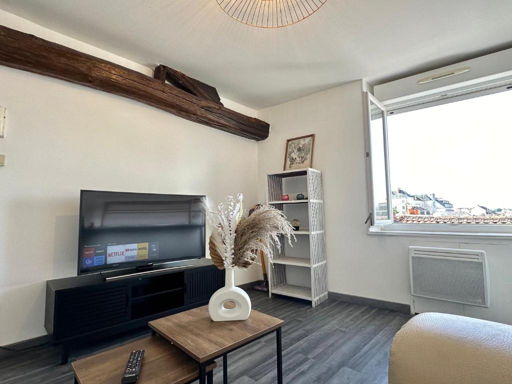 a living room with a flat screen tv and a table at Appartement Cosy en Centre Ville in Cholet