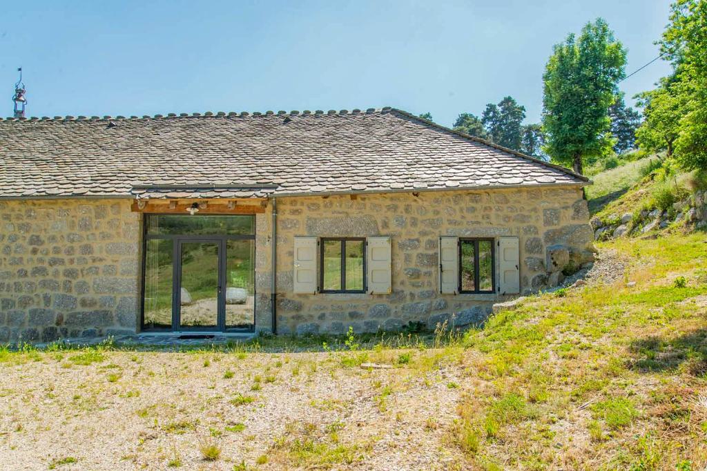 a stone house on a grassy hill at Gite de la grange - domaine de coulagnettes in Serverette