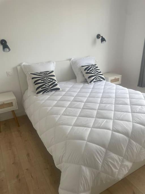 un lit blanc avec deux oreillers dessus dans l'établissement Juan F3 100 m des plages, à Antibes