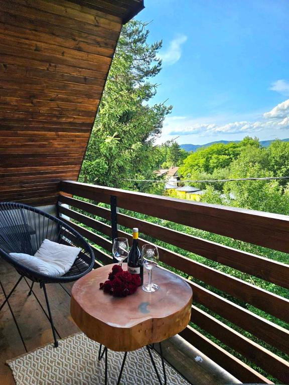 a table with wine glasses and flowers on a balcony at Pyramid Holiday House in Visoko