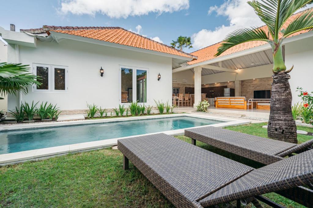 a backyard with a swimming pool and a house at Green Garden Seminyak Villa in Seminyak