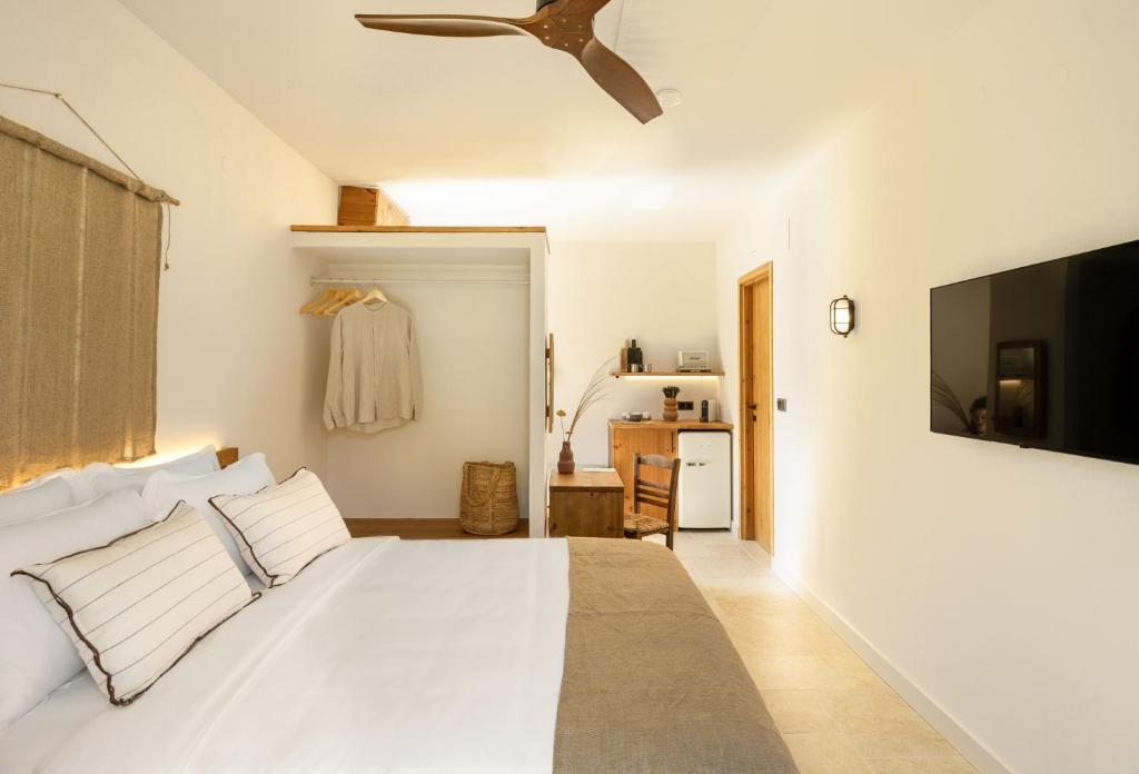 a bedroom with a white bed with a ceiling fan at Ergon Beach House Nikiti in Nikiti