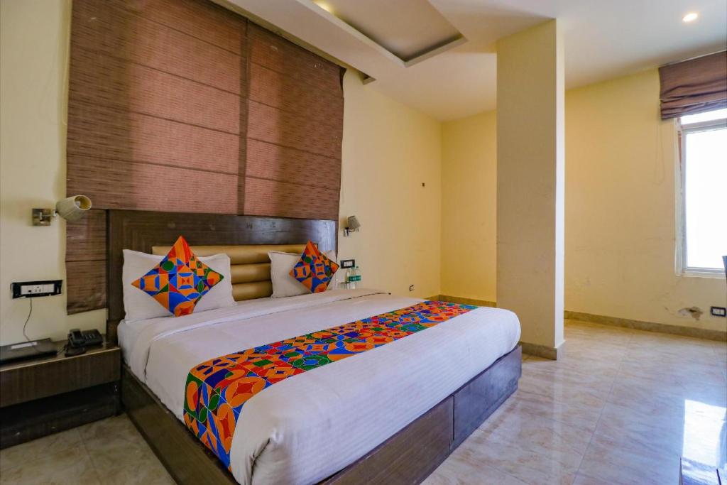 a bedroom with a large bed with colorful pillows at FabHotel Narula in Dehradun