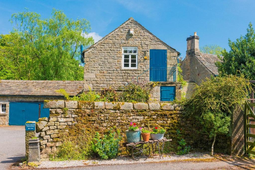 a stone house with blue doors and a stone wall at Heathy Lea BarnChatsworth Estate in Baslow