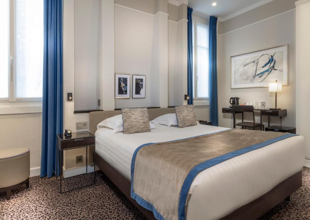 a bedroom with a large bed with blue curtains at Hôtel Du Bois Champs-Elysées in Paris