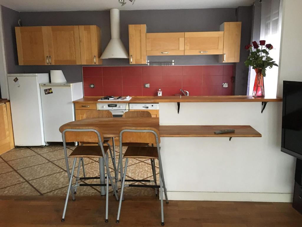 une cuisine avec une table, des chaises et un réfrigérateur dans l'établissement Spacieux et confortable T3 88m2 Grenoble secteur Jeanne d Arc, à Grenoble