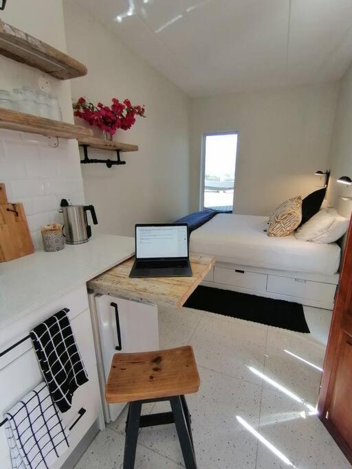 a small room with a bed and a laptop on a desk at Melkbos Sea Spray Studio Apartment in Cape Town