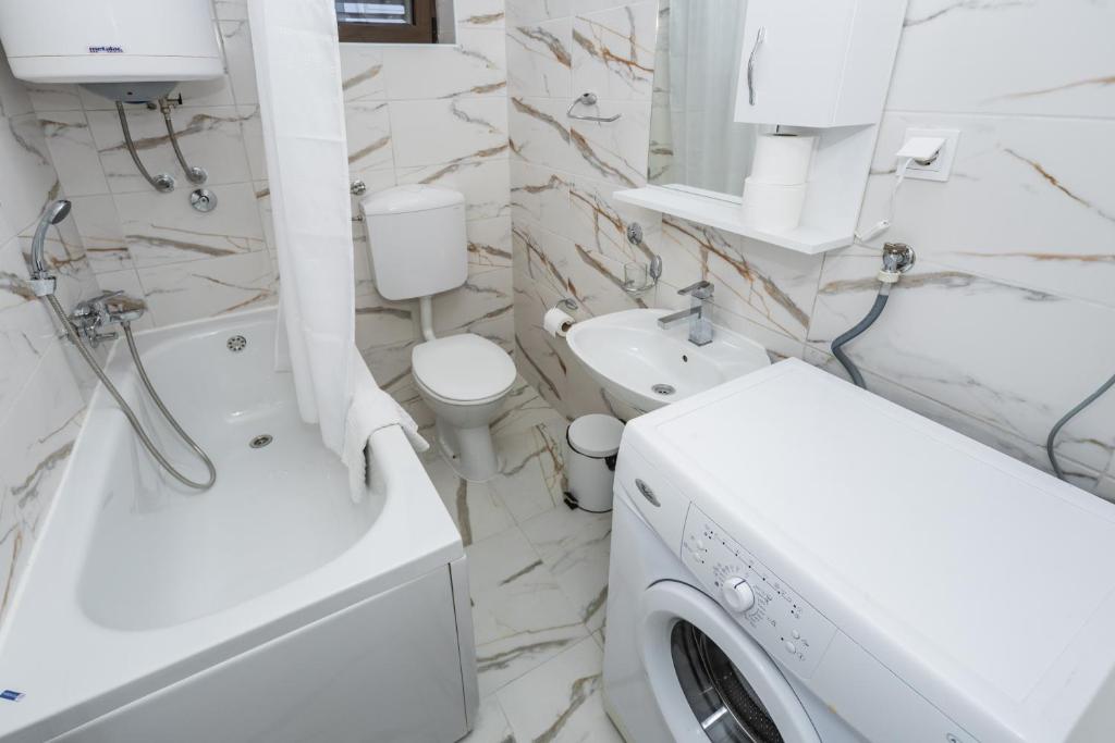 a white bathroom with a washing machine in it at Apartments Raymond in Sveti Stefan