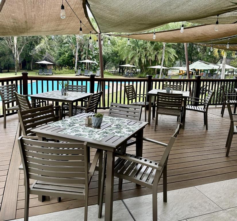 Una terraza de madera con mesas y sillas en un patio. en #523 Kruger Park Lodge, Hazyview, en Hazyview